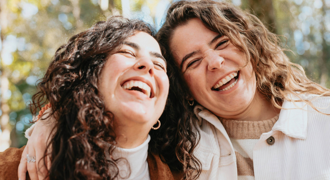 two women arm in arm laughing